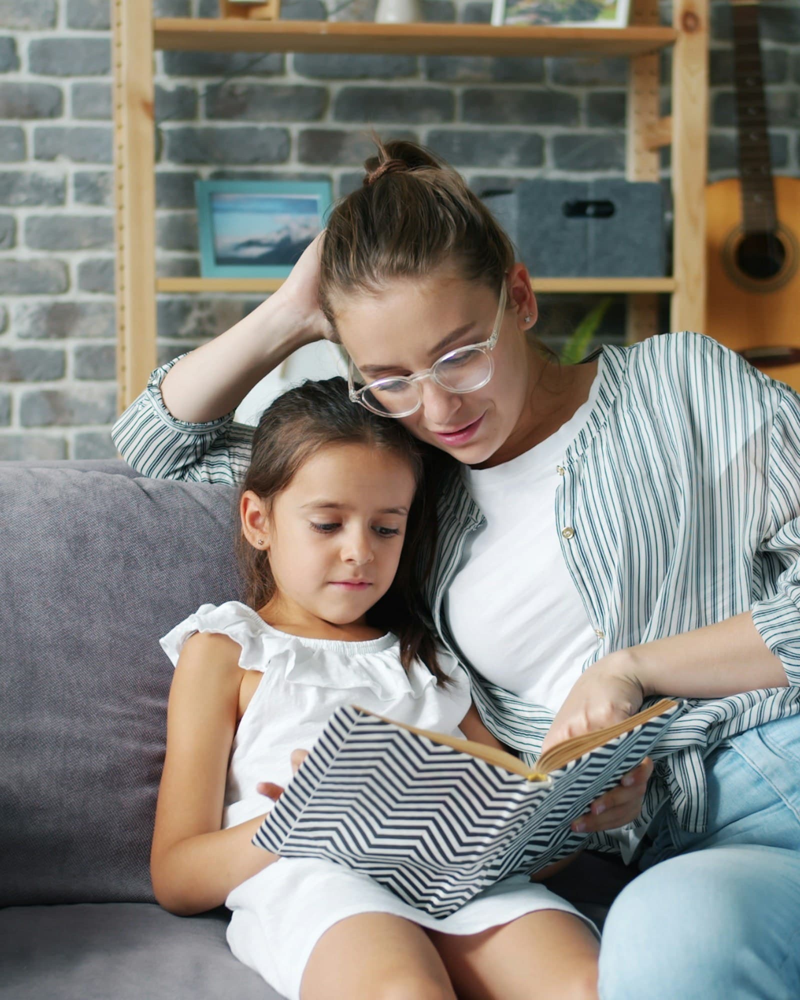 A nanny reading with a child in their living room